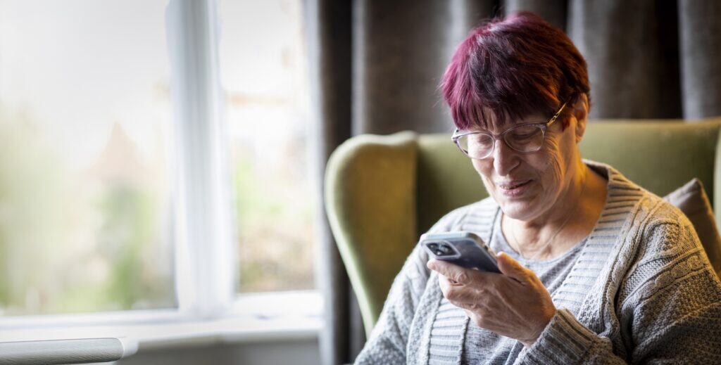 A woman sitting in an armchair checking her phone