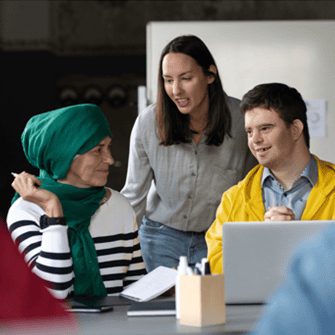 Three people at a table talking with a laptop in front of them