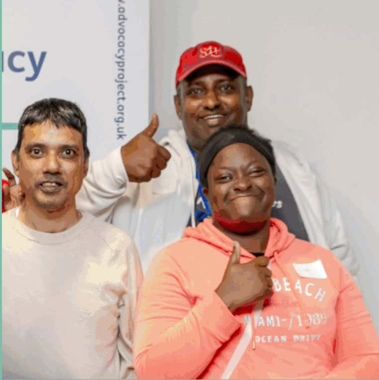 Three people standing together with their thumbs up smiling at the camera