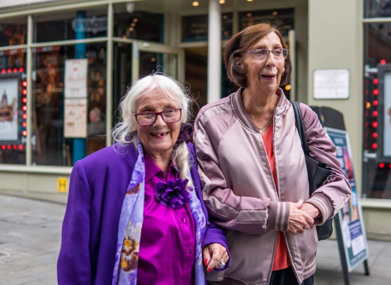 Two women on a street smiling
